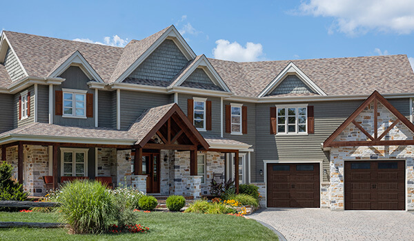 Traditional style house, 2 storeys, stone, wood, shutters, dormer windows, single garage doors with windows in Dark walnut